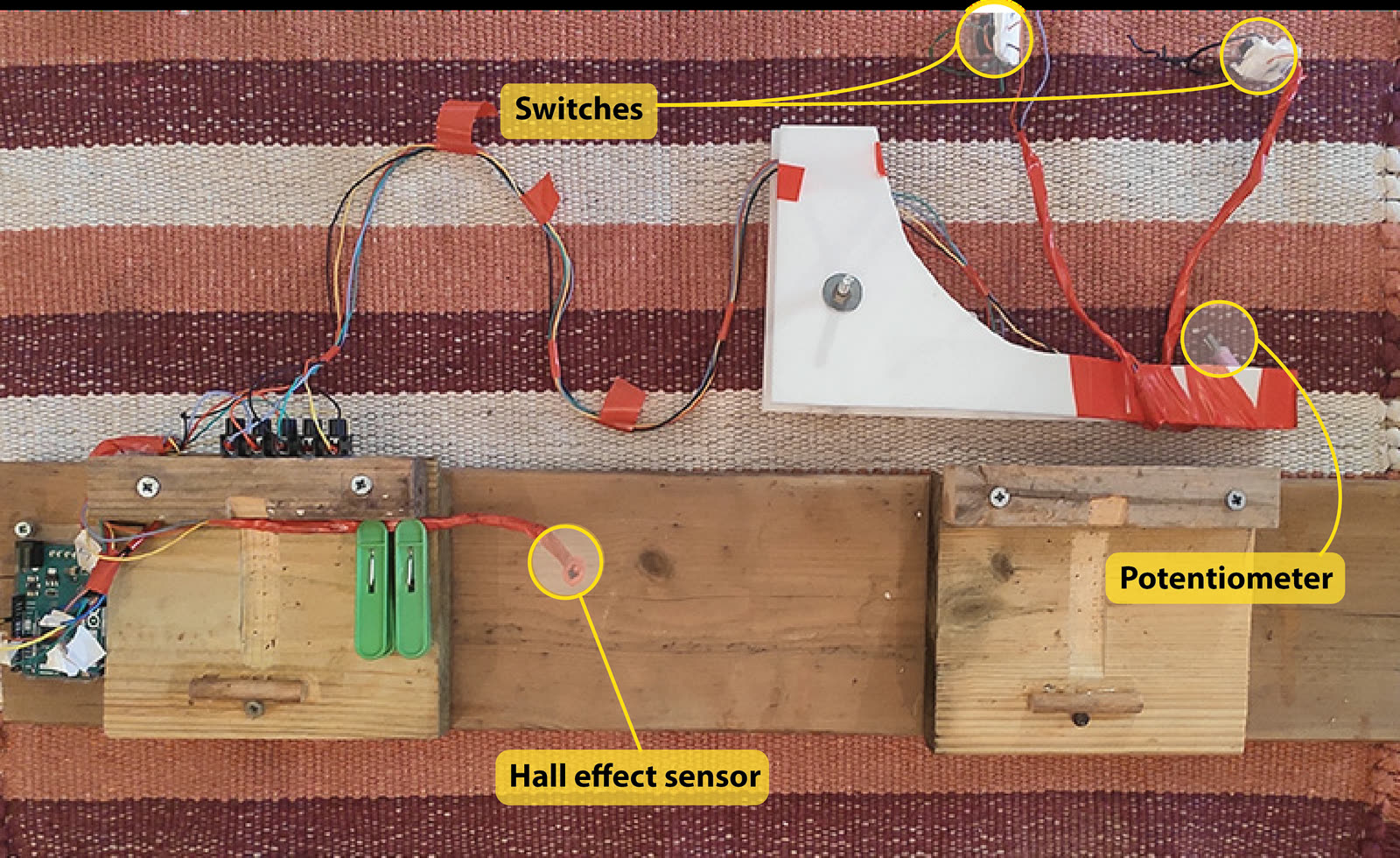 All keyboard-bike components detached and laid out on a rug, with the switches, potentiometer and Hall-effect sensor labeled